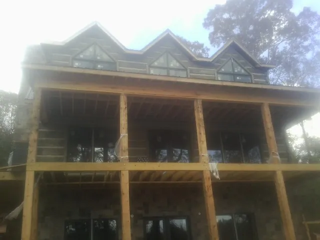 Dormers and porch framing on a large log home under construction — Roof Coating work by our crew in Elkhart